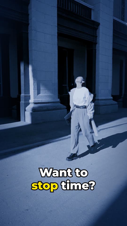 A woman frozen mid-step beside stone columns, the whole picture tinted cool blue.