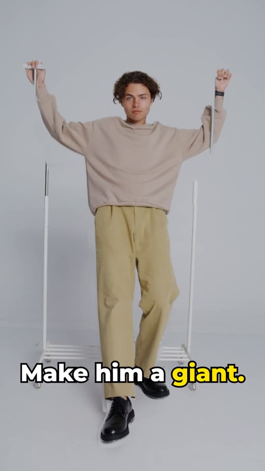 The man at about his normal size in front of the clothes rack.
